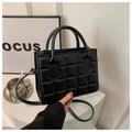 Detalle de la textura acolchada de cuadros negros en un bolso bandolera minimalista - Negro