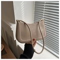 Primer plano del bolso baguette beige minimalista con textura refinada y cremallera metálica - Caqui