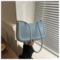 Primer plano de bolso de hombro azul claro con diseño en U y detalles de metal dorado - Azul