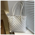 Detail of white quilted leather tote bag showing textured diamond patterns and slim straps - White