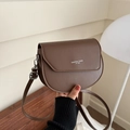 Brown leather saddle bag with white fashion trend text and adjustable shoulder strap - Brown