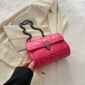 Sac bandoulière matelassé rose vif avec fermoir métallique sur un blazer - Rose rouge
