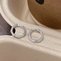 Macro shot of silver hexagonal hoop earring with vertical stripes on paper tray - Silver