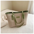 Detail of straw tote bag showing beige herringbone weave and green leather handles - Green