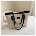 Detail of a beige woven tote bag featuring dark chevron patterns and black leather straps - Black