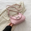 Elegante borsa a tracolla rosa con fiocco argento su uno sfondo di blazer crema - Rosa