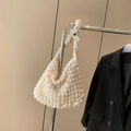 Close-up of white bubble quilted tote bag with 3D texture hanging on metal rack - White