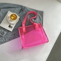 Borsa tote in PVC trasparente rosa neon con accessori moda su un pulito sfondo bianco - Rosa