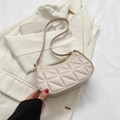 Bolso de hombro acolchado beige con costuras geométricas y cremallera dorada sobre traje - Caqui