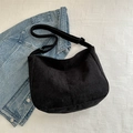 Minimalist black corduroy crossbody bag with adjustable strap on casual denim background - Black