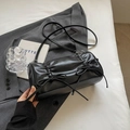 Elegante borsa a cilindro nera pieghettata con fiocchi su sfondo di un abito dai toni neutri - Nero