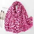 Detail of fuchsia leopard print scarf with fringe edges next to minimalist decor - Pink