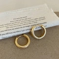 Detalle macro de pendientes de aro geométricos dorados con acabado mate arenado - Pendientes Mate Geométricos / Dorado