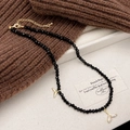 Dettaglio della collana di perline nere con ciondoli a coda di sirena e catena dorata - Stile Coda di Balena con Cristallo Nero