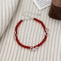 Detail of red agate bead necklace with silver bows on a warm knitted background - Red Agate Bow Bracelet