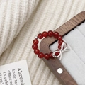 Detailed view of a red agate beaded ring featuring a silver bow charm on a wooden box - Red Agate Bow Ring