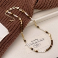 Collana vintage con perle di occhio di tigre marrone su sfondo di maglione marrone - Collana di Perline Occhio di Tigre
