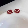 Détail de boucles d'oreilles nœud cœur rouge avec émail brillant sur une assiette - Boucles d'oreilles clous Ancora Red Heart Knot