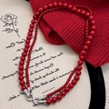 Collana a doppio filo di perle rosse con chiusura a infinito su sfondo romantico - Collana di perle rosse a doppio strato