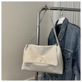 Dettaglio di una borsa bianca in pelle lucida con tracolla a catena e giacca di jeans - Bianco
