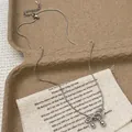 Silberne Schleifen-Halskette mit Schlangenkette und Metallkugeln auf Leinenstoff - Silber