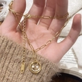 Primer plano del collar con cara sonriente dorada, ojos de perla y detalles de circonitas - Collar con Colgante de Cara Sonriente Dorada con Perlas y Circonitas