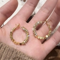 Dettaglio di orecchini a cerchio dorati con cristalli lucidi e dischi metallici - Oro (A-763)