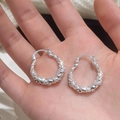 Zilverkleurige gedraaide oorringen met micro-geplaveide zirkoon in een handpalm - Zilver (A-819)
