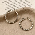 Dettaglio di orecchini a cerchio intrecciati argento su sfondo di carta vintage - Cerchio a corda intrecciata / Oro Caffè