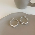 Close-up of silver-tone double-layered hoop earrings with polished beads on a tray - Silver