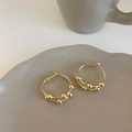 Detailed view of double-layer gold hoop earrings with small beads on a ceramic tray - Gold