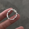 Elastischer Perlenring mit weißen Perlen und silbernen Metallelementen am Finger getragen - Zerkleinerter Silberperlenstil (C-373)