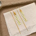 Close-up of golden leaf tassel earrings on rustic burlap background with lyrics - Gold