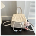 Close-up of cream PU leather mini backpack featuring a drawstring and pink plush charm - White With Pendant / White