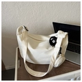 Detail of a beige canvas crossbody bag with mini pouch and coal sprite charm on wood desk - With Pendant / White