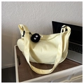 Detail view of a pale yellow crescent bag with wide strap and plush spirit pendant - With Pendant / Yellow