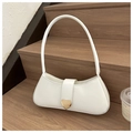 Primer plano de bolso baguette blanco en cuero con hebilla de corazón dorado sobre madera - Blanco