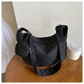 Detail of black crescent crossbody bag with mini round pouch on a wooden table - Black