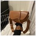 Detail of a brown matte saddle bag featuring a wide nylon strap and gold metal chain - Brown
