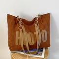 Large brown suede tote bag with HOOIO lettering and chain strap on wooden stool - Coffee