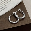 Close-up of silver geometric hoop earrings with metal beads on a wood background - Silver