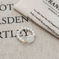 Elegant beaded pearl ring featuring a white rose charm and golden accents on soft fabric - Ring (B-535-Ring)