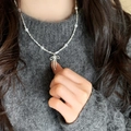 Collana con fiocco d'argento e perle su maglione grigio indossata da modella - Collana Artigianale con Perle d'Argento e Fiocco