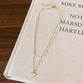 Nahaufnahme einer Doppelhalskette mit Perlen, Goldkette und Herzanhänger-Detail - Gold