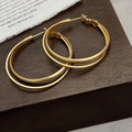 Dettaglio di orecchini a doppio cerchio in metallo opaco dorato su legno scuro - Oro Opaco (A-1205哑光)