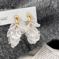 Dettaglio di orecchini d'oro con petali di fiori bianchi su morbido tessuto grigio - Orecchini a Fiore d'Oro