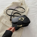 Elegante schwarze Lederhandtasche mit goldener D-Schnalle und Riemen auf beigem Blazer - Schwarz