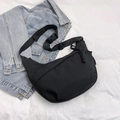 Minimalist black crescent crossbody bag with adjustable strap on casual denim background - Black