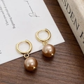 Detail of vintage gold hoop earrings with champagne pearls on a rustic wooden surface - Gold Champagne Faux Pearl