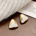 Detail of geometric triangle gold earrings with white enamel finish on a knit sweater - White